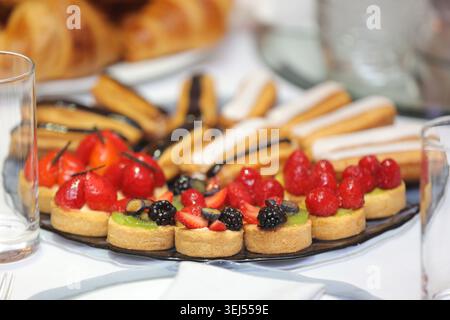 Assorted Mini Fruit Tarts and Eclairs on Dessert Platter Stock Photo