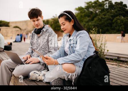 Students using laptop and studying together outdoors Stock Photo
