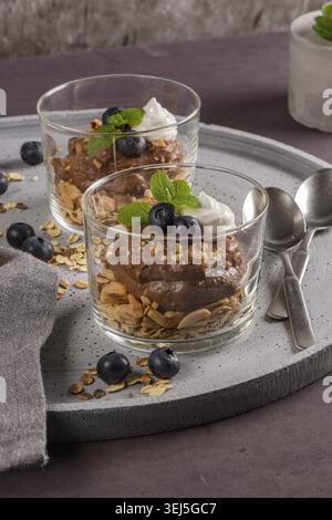 Glass cups of chocolate and chestnuts mousse with roasted almonds and oats decorated with black berries and mint leaves Stock Photo