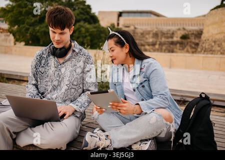 Students using laptop and studying together outdoors Stock Photo