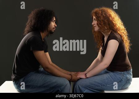 Young diverse couple communicating while holding hands, symbolizing connection and trust Stock Photo