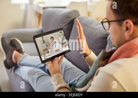 Sick young man using digital tablet for online telemedicine consultation with doctor via video call. Stock Photo