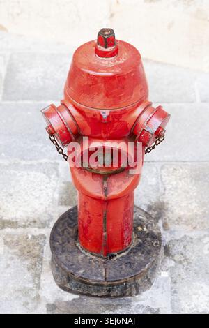 Venice, Veneto - Italy - 06-09-2021: Vibrant but aging red fire hydrant stands on weathered stones in Venice Stock Photo