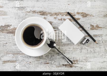 Still life with coffee. Coffee cup, bank business cards, spoon, pencil and sharpener on wooden table background. Top view Stock Photo