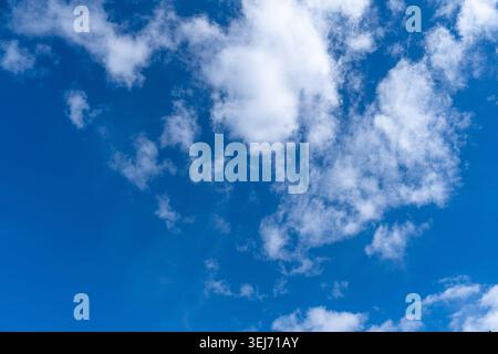 Blue sky with fluffy white clouds on a bright sunny day, serene cloudscape scenery in daylight Stock Photo