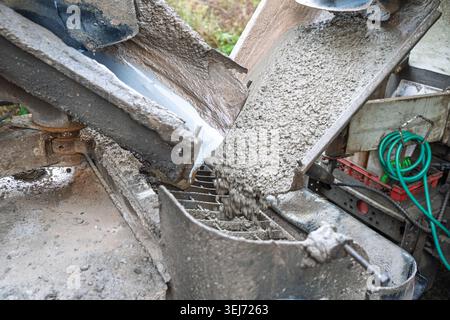 Pouring wet concrete from mixer truck into pump at construction site, industrial building and m Stock Photo