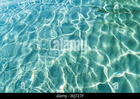 Sunlit crystal clear turquoise water and sand patterns in Sardinia, Italy, reflecting bright, d Stock Photo