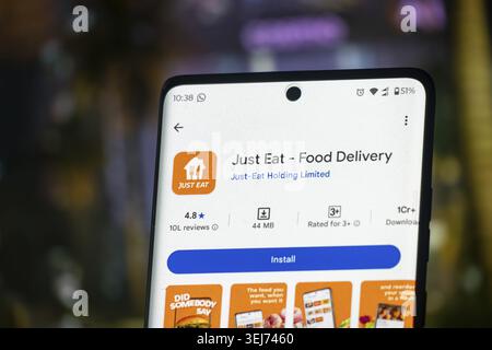 Dhaka, Bangladesh 26 Dec 2025:Just eat application icon on black screen of smartphone with white plastic forks on yellow background Stock Photo