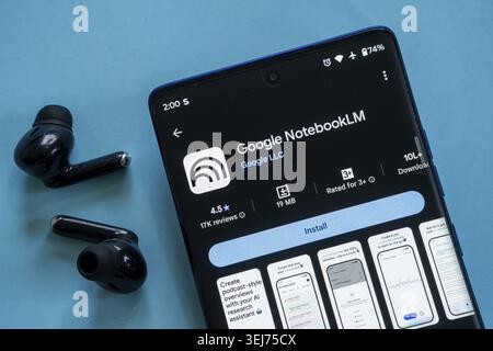 Dhaka, Bangladesh 23 August 2025:Smartphone displaying Google NotebookLM app with black earbuds on a blue background Stock Photo