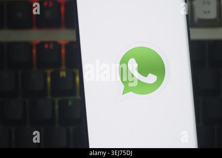Dhaka, Bangladesh 23 August 2025:Phone displaying WhatsApp icon with glowing keyboard in the background Stock Photo