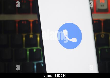 Dhaka, Bangladesh 23 August 2025:A smartphone displays a blue phone app icon against a white background over a colorful keyboard Stock Photo