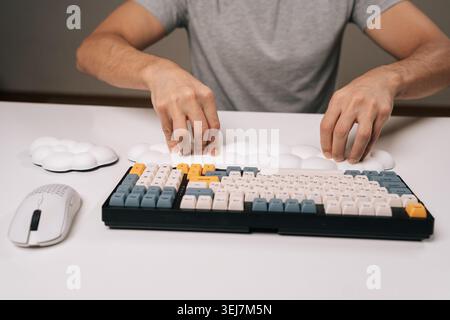 Close-up of man placing cloud-shaped wrist rest for ergonomic comfort while using mechanical keyboard and wireless mouse on clean white desk Stock Photo