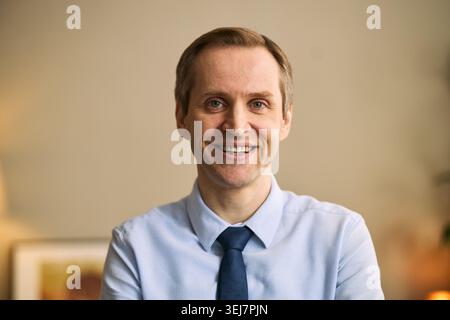 Portrait of middle aged Caucasian businessman smiling at camera, conveying trust, confidence, professional approachability. Ideal for leadership, teamwork, male friendship campaigns Stock Photo