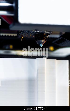3D printer nozzle creating object in workshop during day Stock Photo