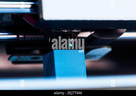 3D printer working on creating a blue object at close range in a workshop setting Stock Photo