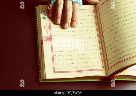 Hand holds open book with handwritten text and beads beside it Stock Photo