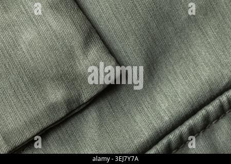 Close-up of folded green fabric revealing detailed textile texture, padded quilting and visible stitching; versatile background for design, upholstery Stock Photo