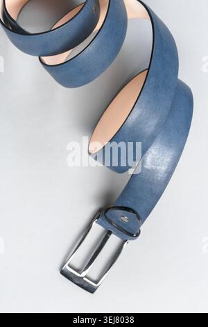 Blue leather belt laying on a light surface with a silver buckle in view Stock Photo