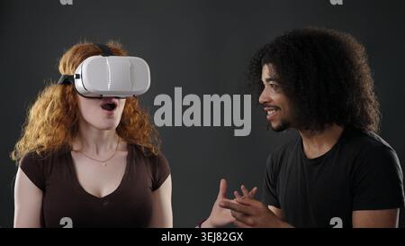 Young woman experiencing virtual reality as man interacts with her Stock Photo