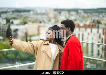 Stylish confident african american man and woman tourists taking selfie on phone at local attraction Stock Photo