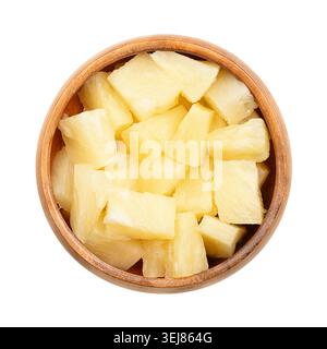 Canned pineapple chunks, in a wooden bowl. Ripe pineapples, cut into block shaped pieces, boiled in its own juice, and then tinned. Stock Photo