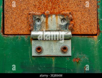 A close-up view showcases a rusty metal hinge on an old, green door. The textures convey layers of history and time, illuminated beautifully by the af Stock Photo
