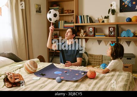 Father and Son Playing with Soccer Ball during Learning at Home Stock Photo