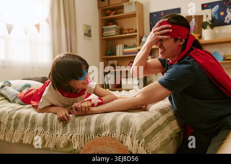 Father and Son Playing Pretend Superhero Game for Family Bonding Stock Photo