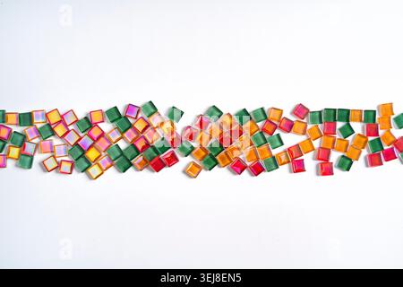 a strip of colored glass tiles scattered on a white background Stock Photo
