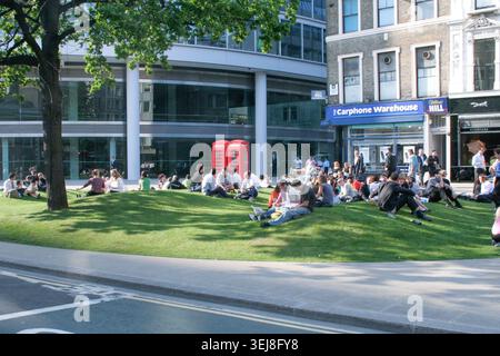 City of London employees taking a springtime lunch break on the lawns at Moorfields in front of the modern Moor House building (Moorgate) in April 200 Stock Photo