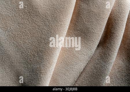 Close up of premium beige suede or faux nubuck fabric arranged in elegant folds. Luxury textile material background for fashion, interior design, and Stock Photo