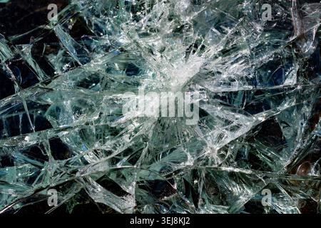 Shattered glass texture background with cracks macro. Close up view of shattered and cracked safety glass on a dark background. Abstract broken window Stock Photo