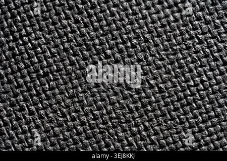 Close up of a black textured surface with an embossed woven pattern creating geometric light reflections and shadows Stock Photo