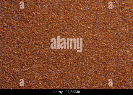 Brown sandpaper texture close up background. Macro texture of brown abrasive sandpaper sheet surface with rough grit material creating a detailed patt Stock Photo