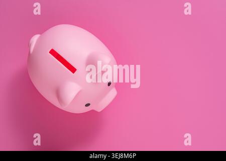 Pink piggy bank on pink background with copy space top view. Minimalist top view of a cute pink piggy bank on a matching pink background with blank sp Stock Photo