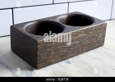 Black oak salt and pepper pinch pot sitting on a marble countertop against a white, metro tile wall. Stock Photo