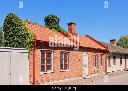 Idyllic Old brick house on a city street with climbing ivy plants Stock Photo