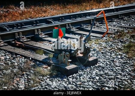Close-up side view of a vintage mechanical railway track switch lever and green-and-red target signal on wooden ties, railroad infrastructure Stock Photo