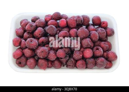 Food storage in freeze. Top view. Frozen cherries in a white container isolated on a white background. Defrosting. Saving vitamins. Stock Photo