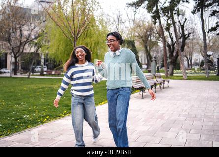 Two young women walking together along park path Stock Photo