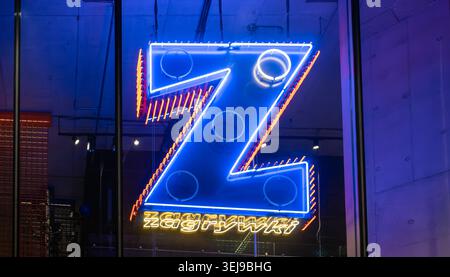 A bright blue neon letter Z is illuminating at a dark urban storefront window. Stock Photo