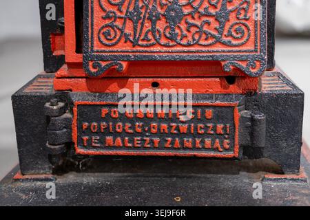 A close-up view of a black and red cast-iron stove door featuring Polish text instructions. Stock Photo