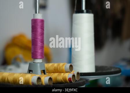 Colorful sewing thread cones and yarn spools arranged on a textile machine in a garment manufacturing unit, highlighting textile production. Stock Photo