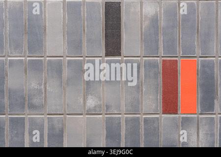 Colorful accent tiles are set into a grey rectangular tiled exterior wall. Stock Photo