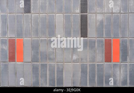 Symmetrical colored accent tiles are positioned in a grey rectangular tiled building exterior. Stock Photo
