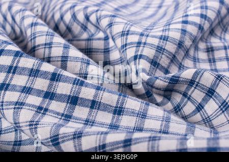 Close-up of blue and white yarn tie dyed check fabric with soft folds and textured weave, showcasing traditional textile craftsmanship. Stock Photo