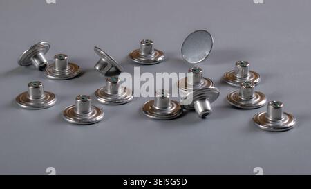 Assorted metal snap fasteners arranged on a white background, close-up view of garment hardware used in tailoring, sewing, clothing manufacturing Stock Photo