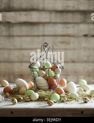A rustic basket filled with farm-fresh chicken and quail eggs on straw, styled in a natural farmhouse setting. Stock Photo