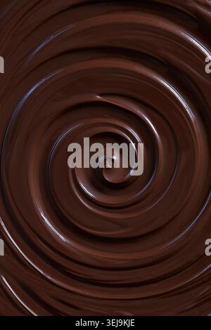 Smooth, glossy liquid dark chocolate swirling in a rich spiral, showcasing a luxurious melted chocolate texture in close-up. Stock Photo