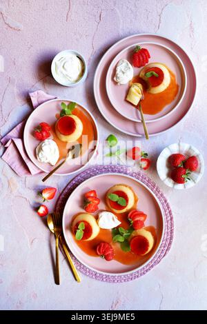 Crème caramel classic French custard dessert topped with a layer of soft caramel sauce and served with strawberries, apple mint and whipped cream. Stock Photo